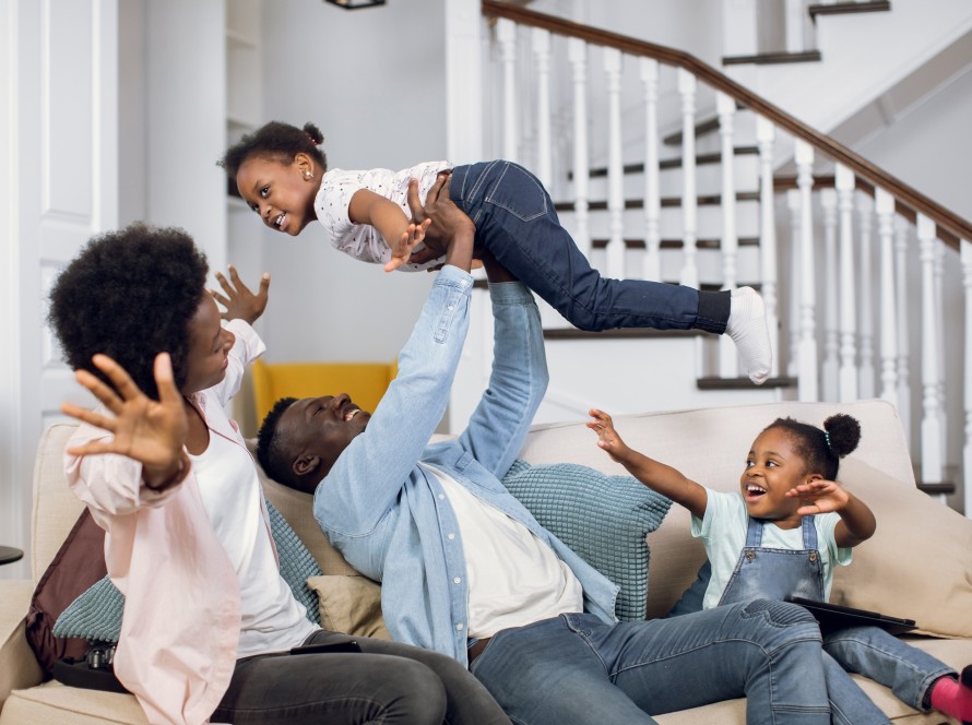 African parents playing with two daughters on couch